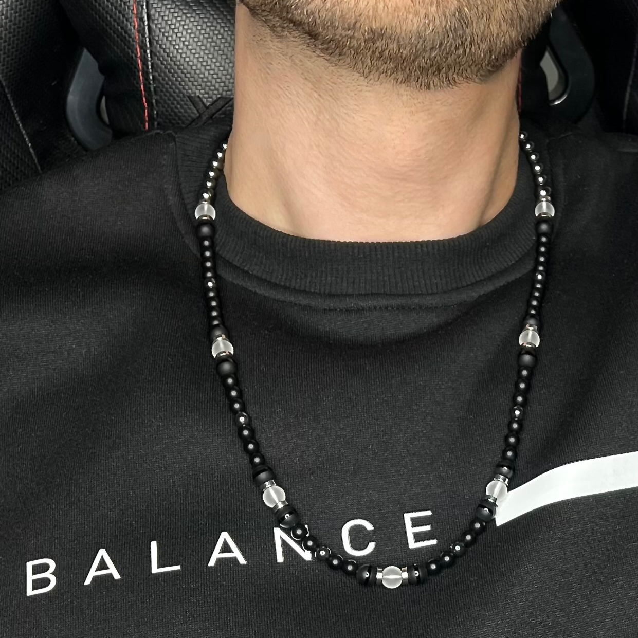 Stylish men’s necklace with Onyx, Clear Quartz, and Hematite, worn by a model, perfect accessory for professionals and ambitious individuals. Stylish men’s necklace with Onyx, Clear Quartz, and Hematite, worn by a model, perfect accessory for professionals and ambitious individuals.