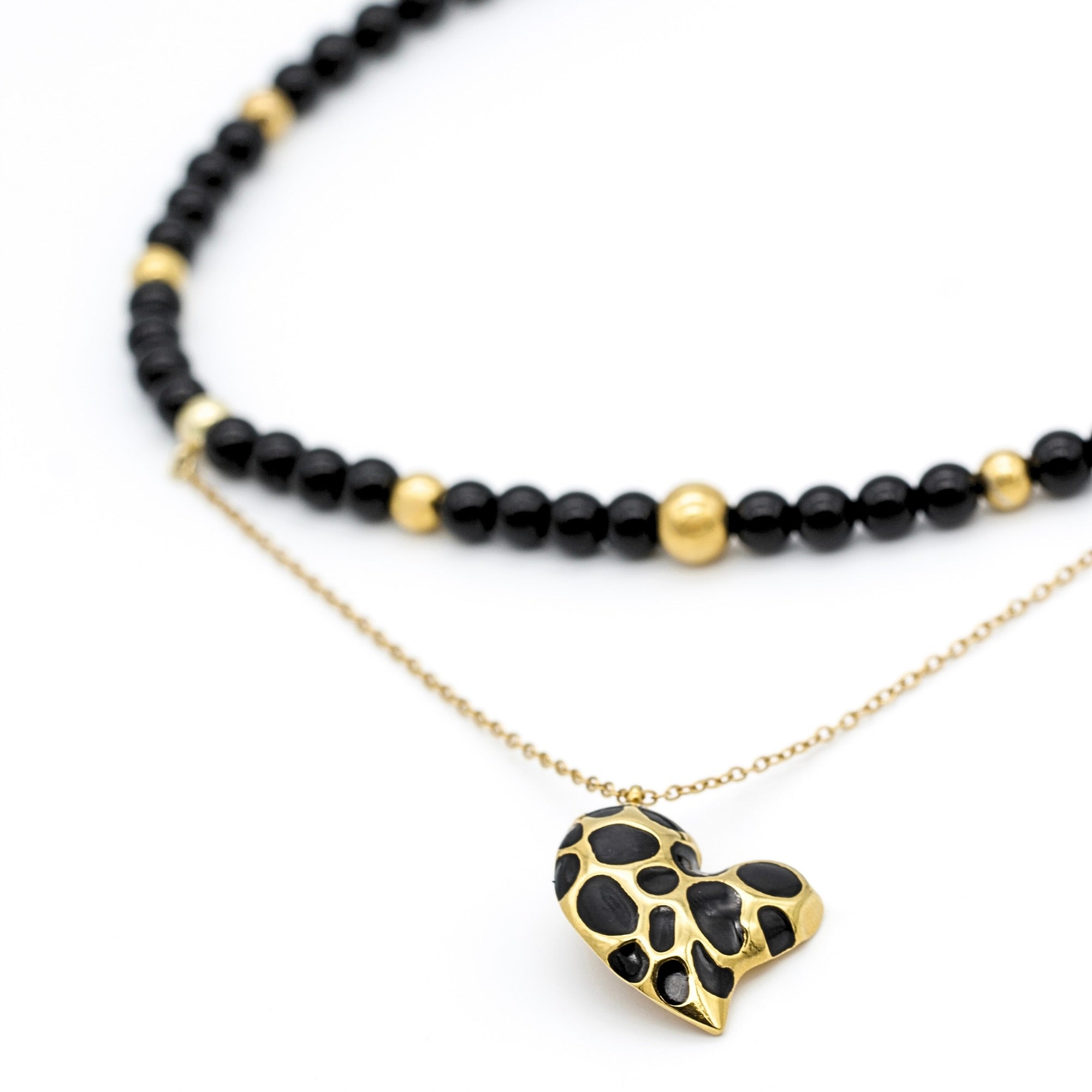 Close-up of onyx and black tourmaline beads with gold heart pendant in women's choker