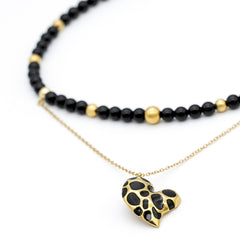 Close-up of onyx and black tourmaline beads with gold heart pendant in women's choker
